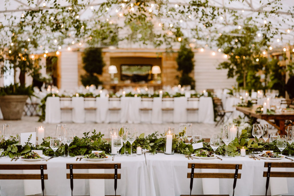 reception setup in the greenhouse at long hollow gardens featuring lots of greenery and white linens