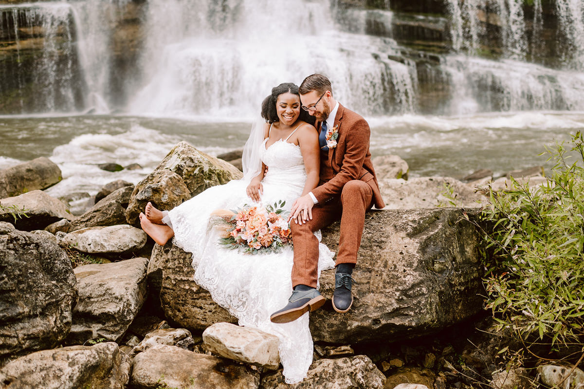 just married couple sitting on the rocks in front of twin falls at their rock island state park elopement